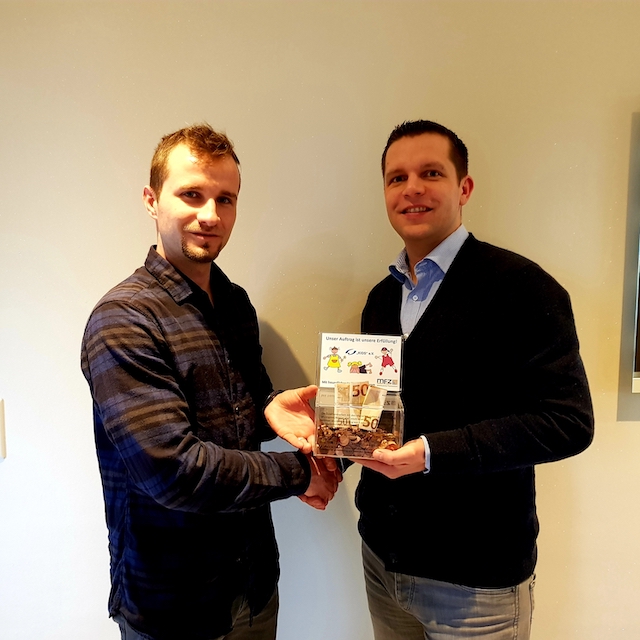 Foto von zwei Männern, die eine Spende überreichen.