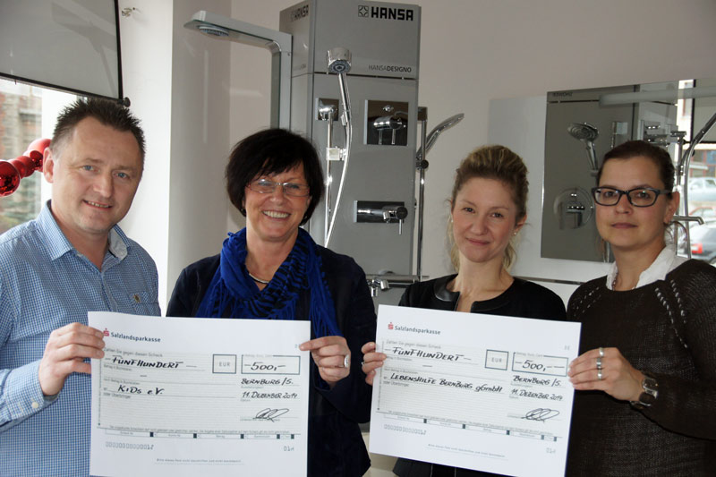 Foto von vier Personen, die Checks hochhhalten.